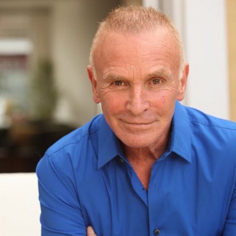 Portrait of Dr. Jonny Bowden in a blue shirt, arms folded, smiling